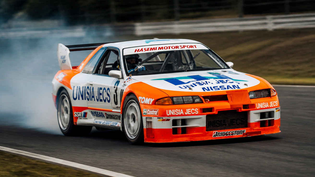 Carro de rali Nissan azul e laranja a derrapar numa pista de corrida, com fumo a sair dos pneus.